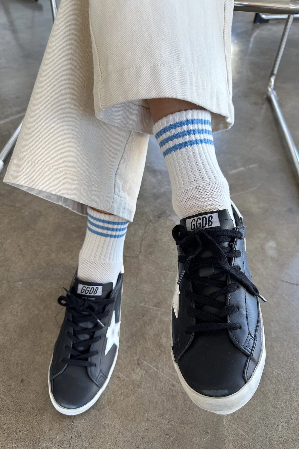 woman in sneakers and white ankle socks with three light blue stripes