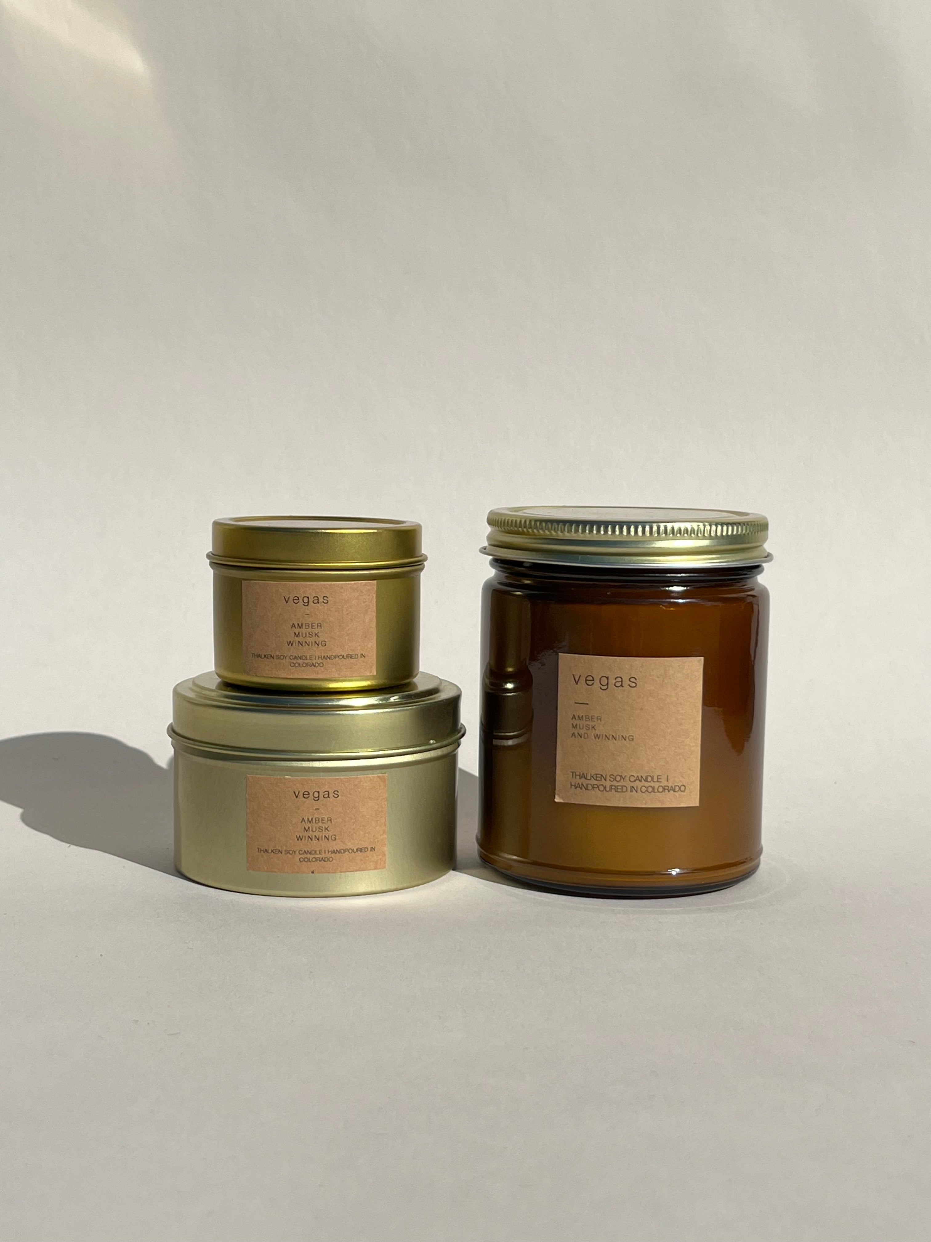 Vegas scented soy candles in gold metal tins and brown glass container 