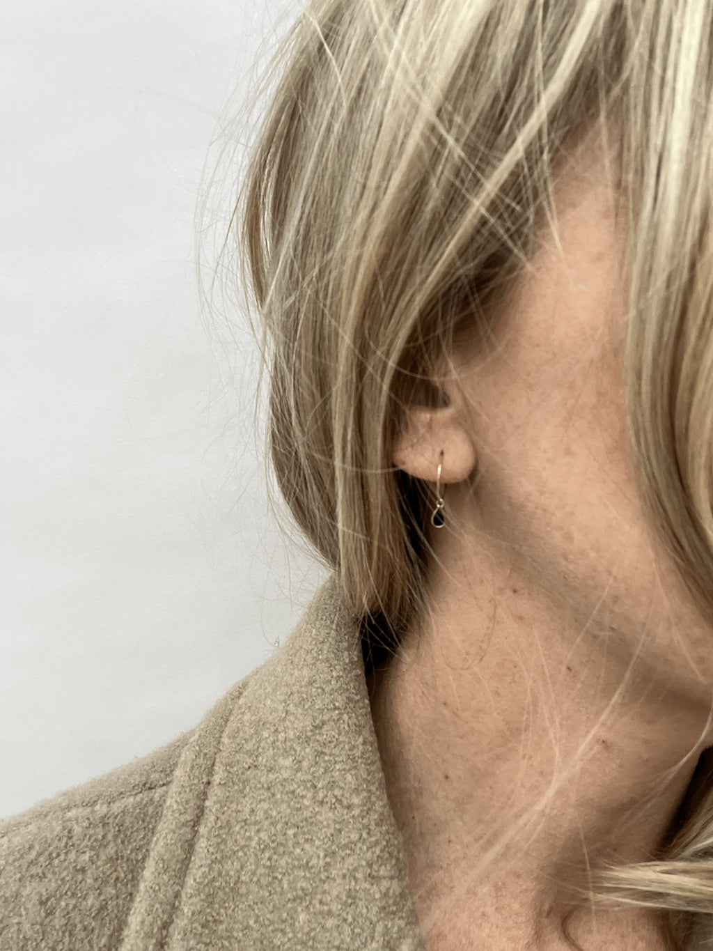 Model wearing Thalken 14k gold 12mm hoop earring with a small pear-shaped black spinel drop