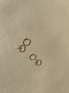 Two pairs of Thalken’s 14k solid gold dainty hoop earrings on a neutral background, showing both 10mm and 12mm sizes