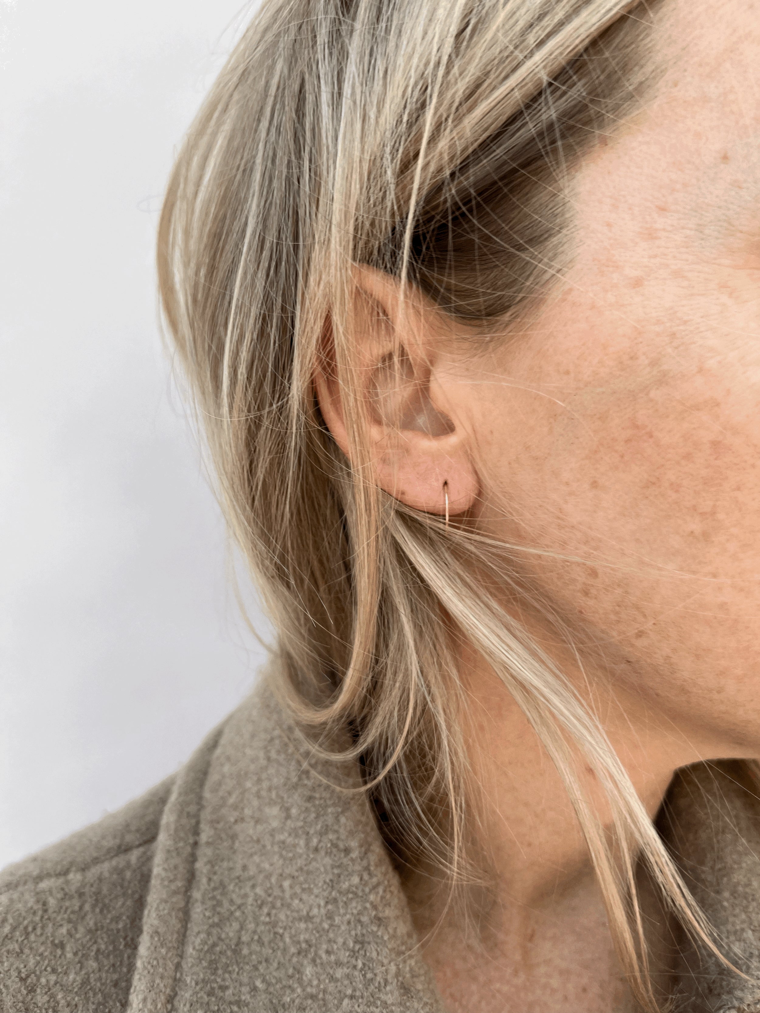 Model wearing Thalken’s 14k solid gold 12mm dainty hoop earring in her first ear piercing for a minimalist everyday look