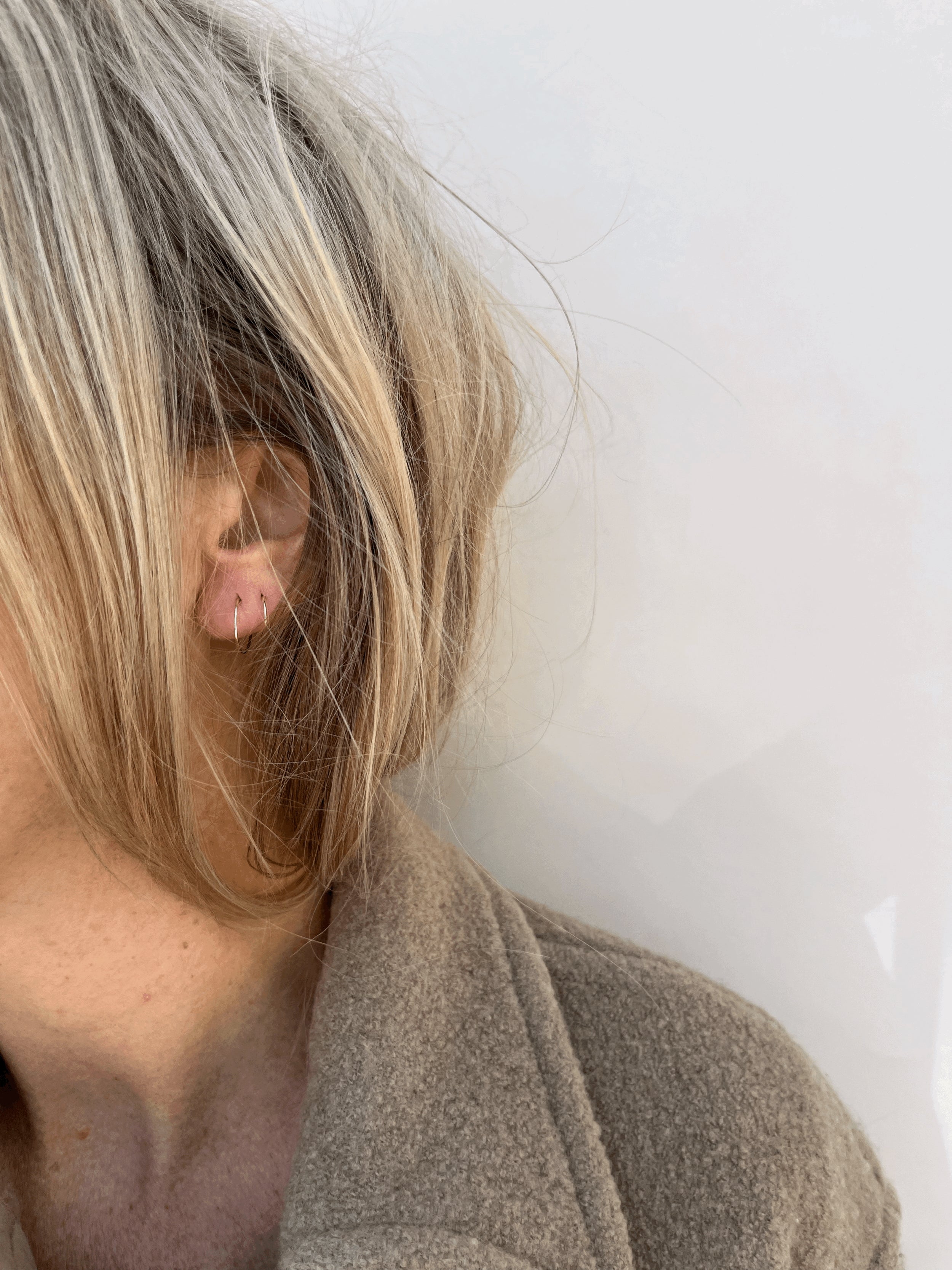Model wearing Thalken’s 14k solid gold 12mm dainty hoop earring in her first ear piercing and 10mm dainty hoop in her second piercing