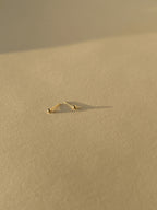 Close-up of 2mm 14k solid gold ball stud earring pair on a neutral background, highlighting their petite size and polished finish