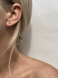 Model wearing the 4mm 14k solid yellow gold heart stud in her first ear piercing and the 3mm heart stud in her second ear piercing