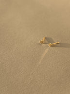 Pair of 14k solid yellow gold 3mm heart stud earrings displayed on a neutral background from different angles