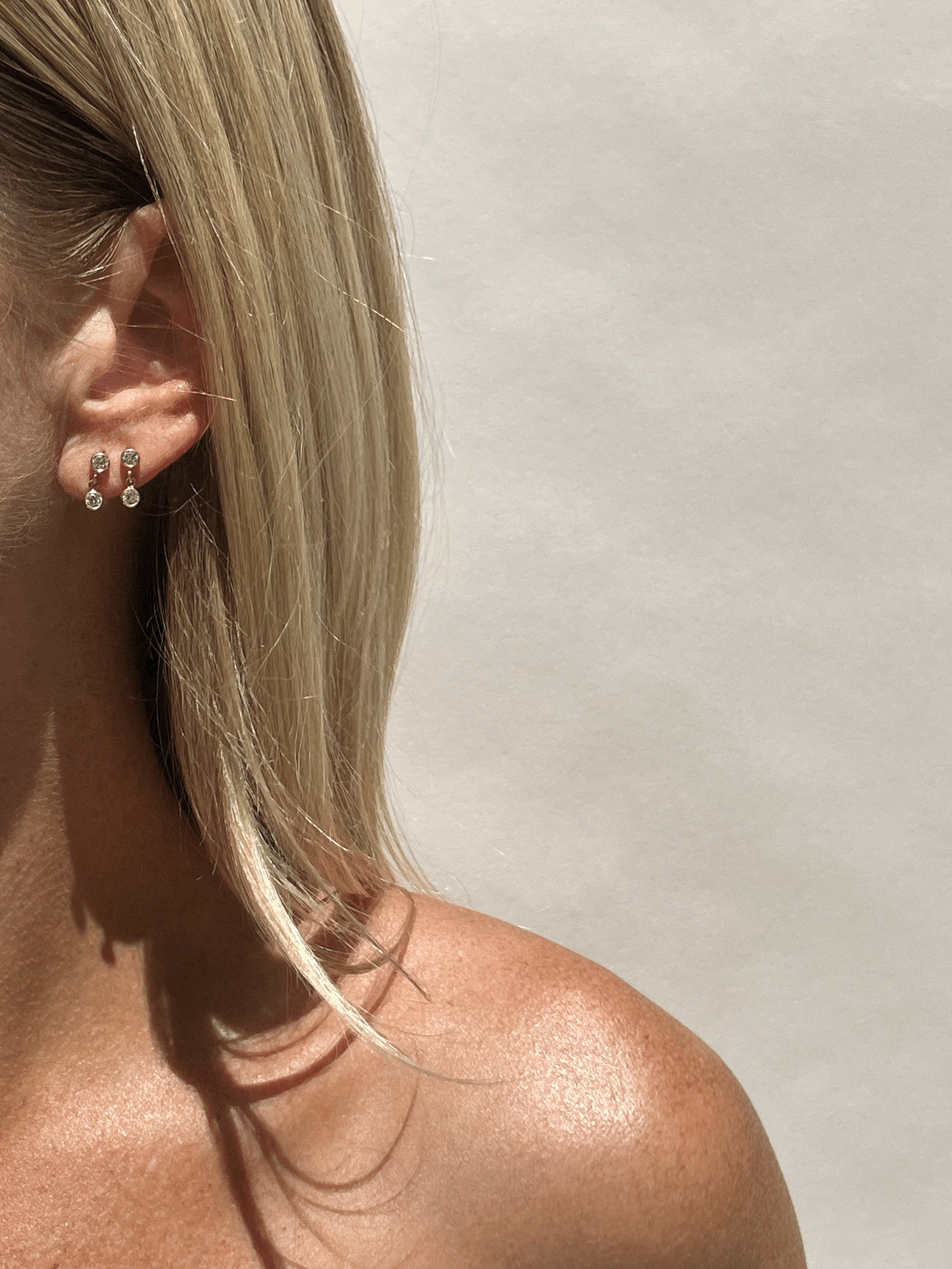 Model wearing Thalken’s 3mm gold-filled cubic zirconia stud and drop earrings in first and second piercings for a layered minimalist look