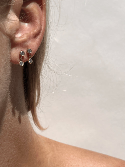  Close-up of model wearing Thalken’s gold-filled cubic zirconia stud and drop earrings, showcasing the dainty sparkle and drop detail