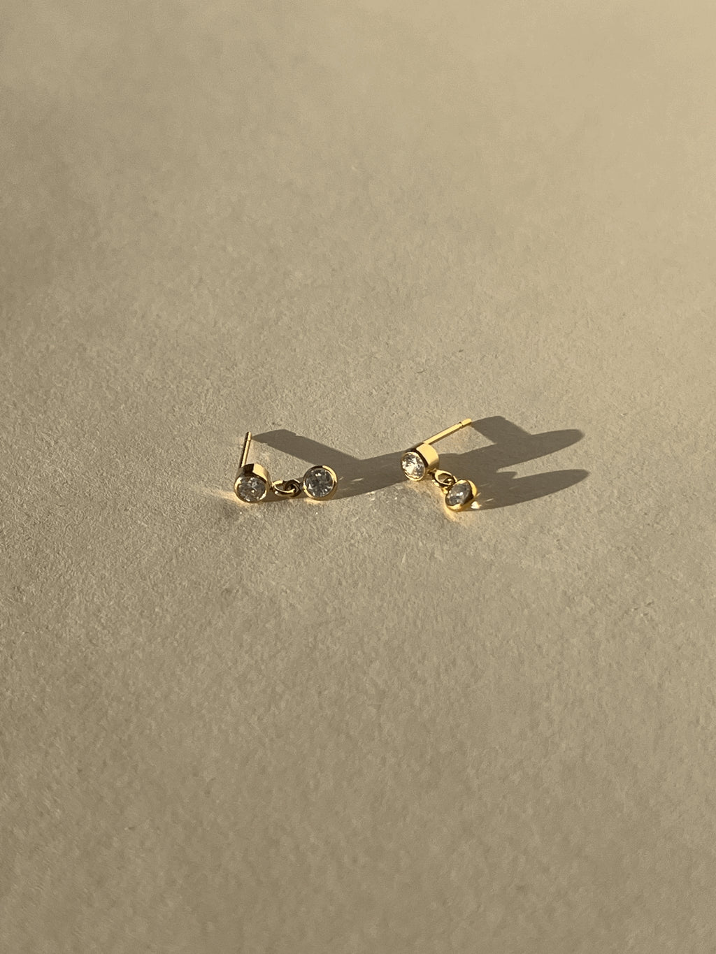 Product shot of Thalken’s 3mm gold-filled cubic zirconia stud and drop earrings on a neutral background, showing pair layout
