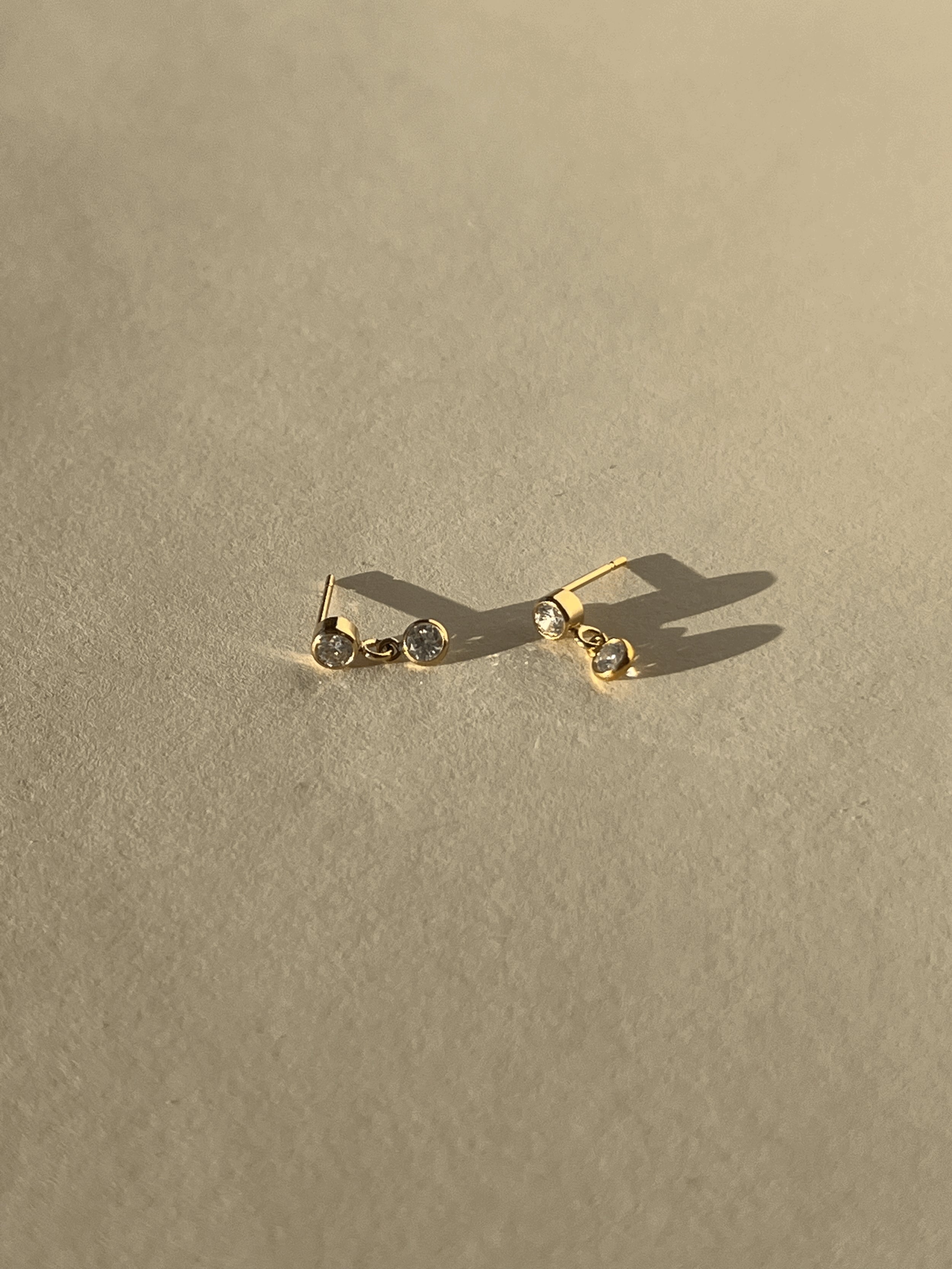 Product shot of Thalken’s 3mm gold-filled cubic zirconia stud and drop earrings on a neutral background, showing pair layout