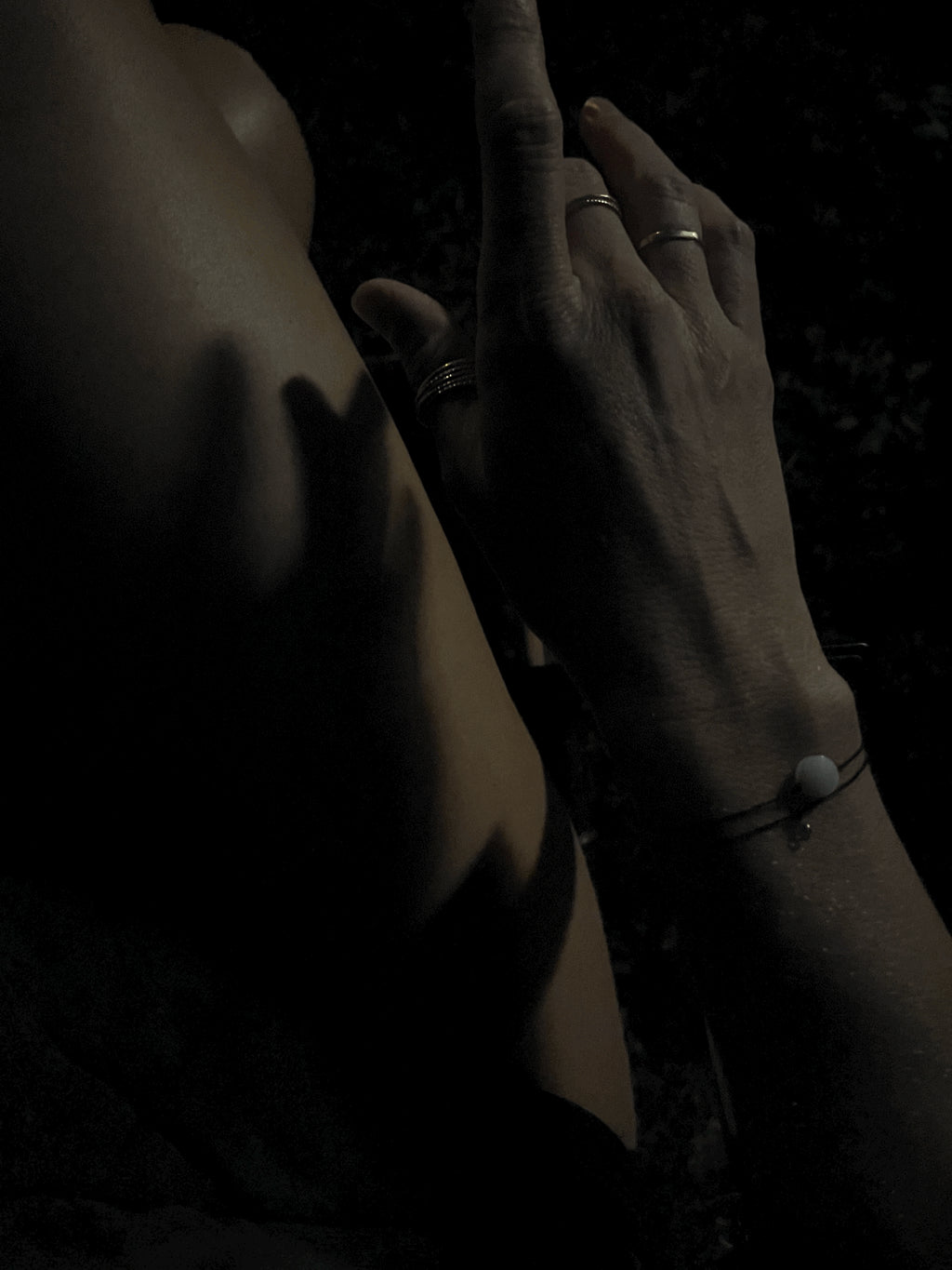 Bird’s-eye view at night of model in white pajama shorts wearing the Thalken® sparkle mantra bracelet paired with the Moon Charged bracelet