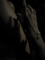 Bird’s-eye view at night of model in white pajama shorts wearing the Thalken® sparkle mantra bracelet paired with the Moon Charged bracelet