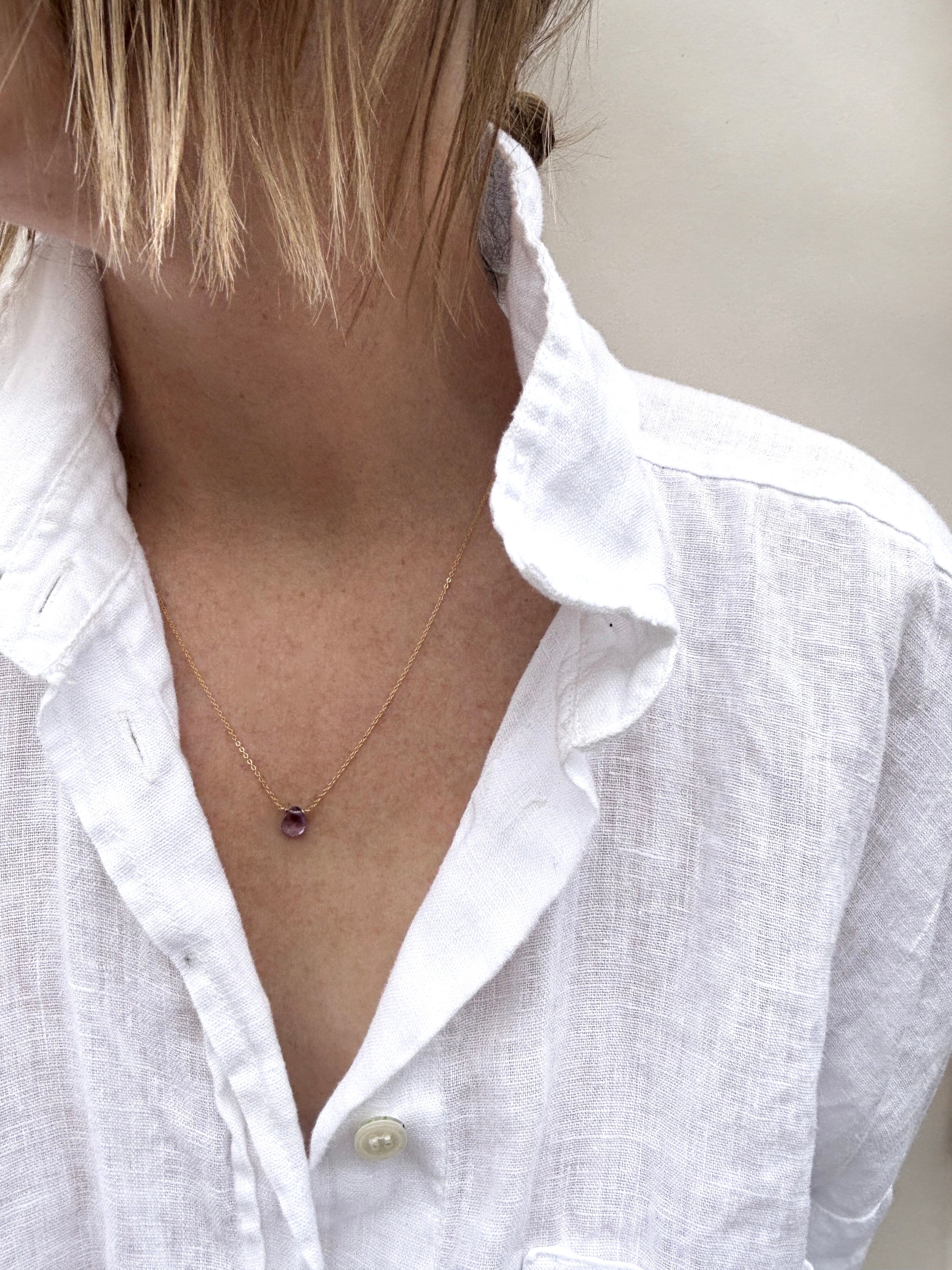 Woman wearing dainty Thalken amethyst drop necklace in white linen button down shirt