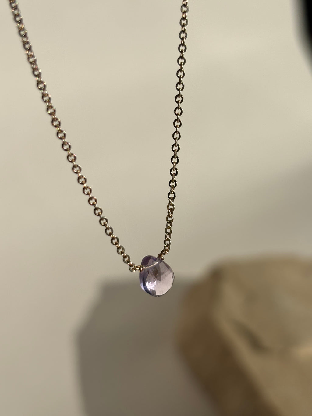 Natural purple amethyst drop stone fixed on dainty yellow gold-filled chain suspended in air