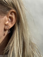 Model wearing Thalken 14k solid gold 12mm hoop earring with a small marquise-shaped natural amethyst drop in the first ear piercing, paired with a 10mm hoop with a matching marquise amethyst drop in the second piercing