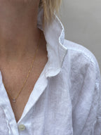 Dainty Thalken aquamarine drop necklace on woman wearing white linen button down shirt