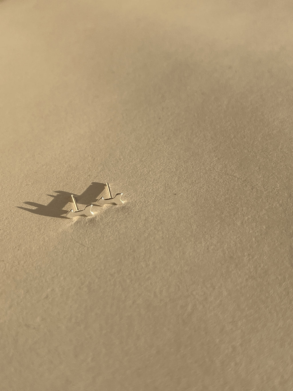 Pair of sterling silver arrow stud earrings shown on a light backdrop