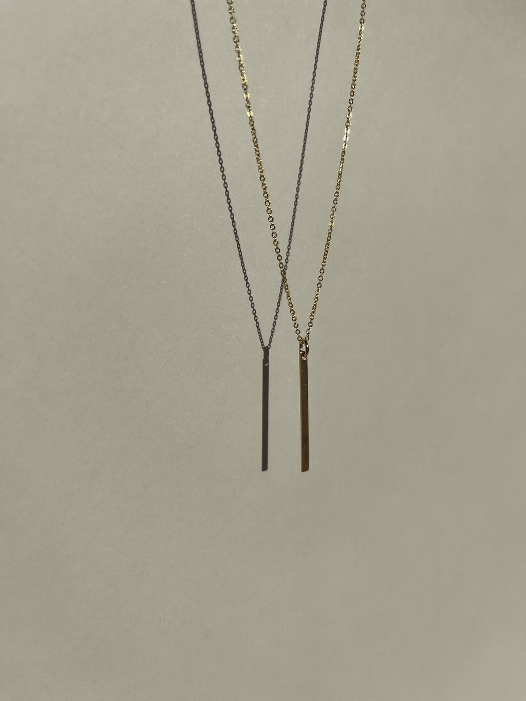 Yellow gold-filled Bar Necklace suspended in air, warm light against a neutral backdrop