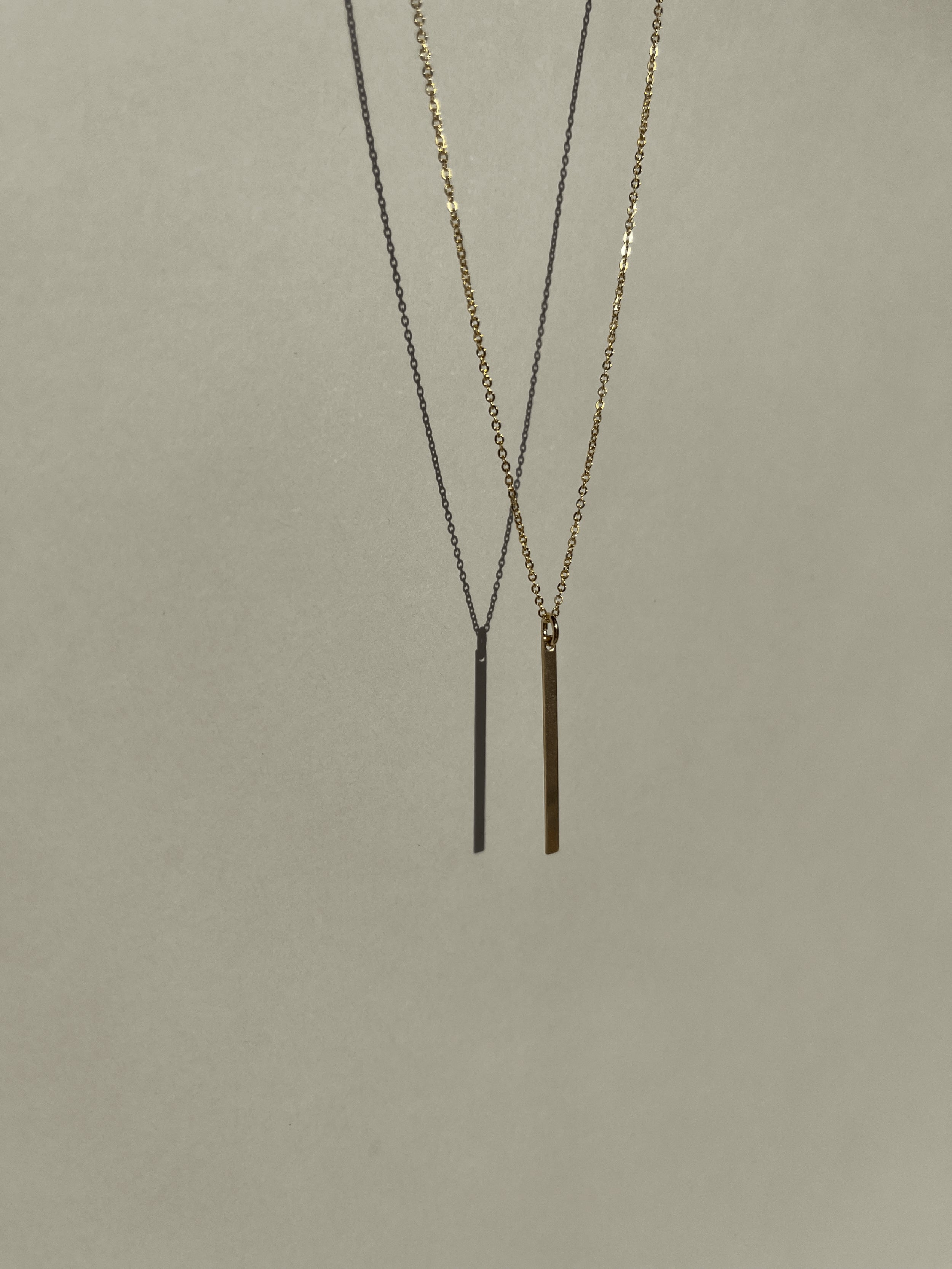 Yellow gold-filled Bar Necklace suspended in air, warm light against a neutral backdrop