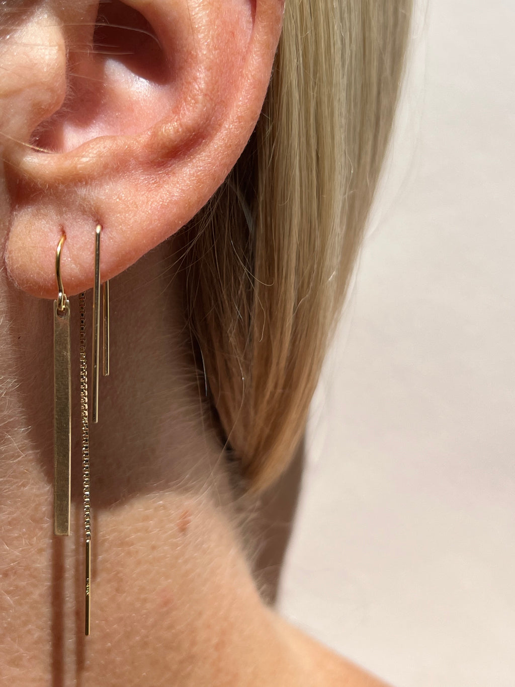 Model wearing Thalken’s Bar Threader Earring in yellow gold-filled in her first piercing, paired with the Long Petite Staple Earring in yellow gold-filled in her second piercing