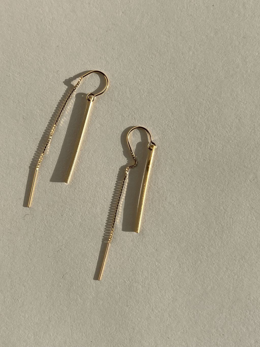 Yellow gold-filled Bar Threader Earrings displayed on a cream background, shown from the front angle highlighting their sleek minimalist design