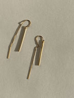 Yellow gold-filled Bar Threader Earrings displayed on a cream background, shown from the front angle highlighting their sleek minimalist design