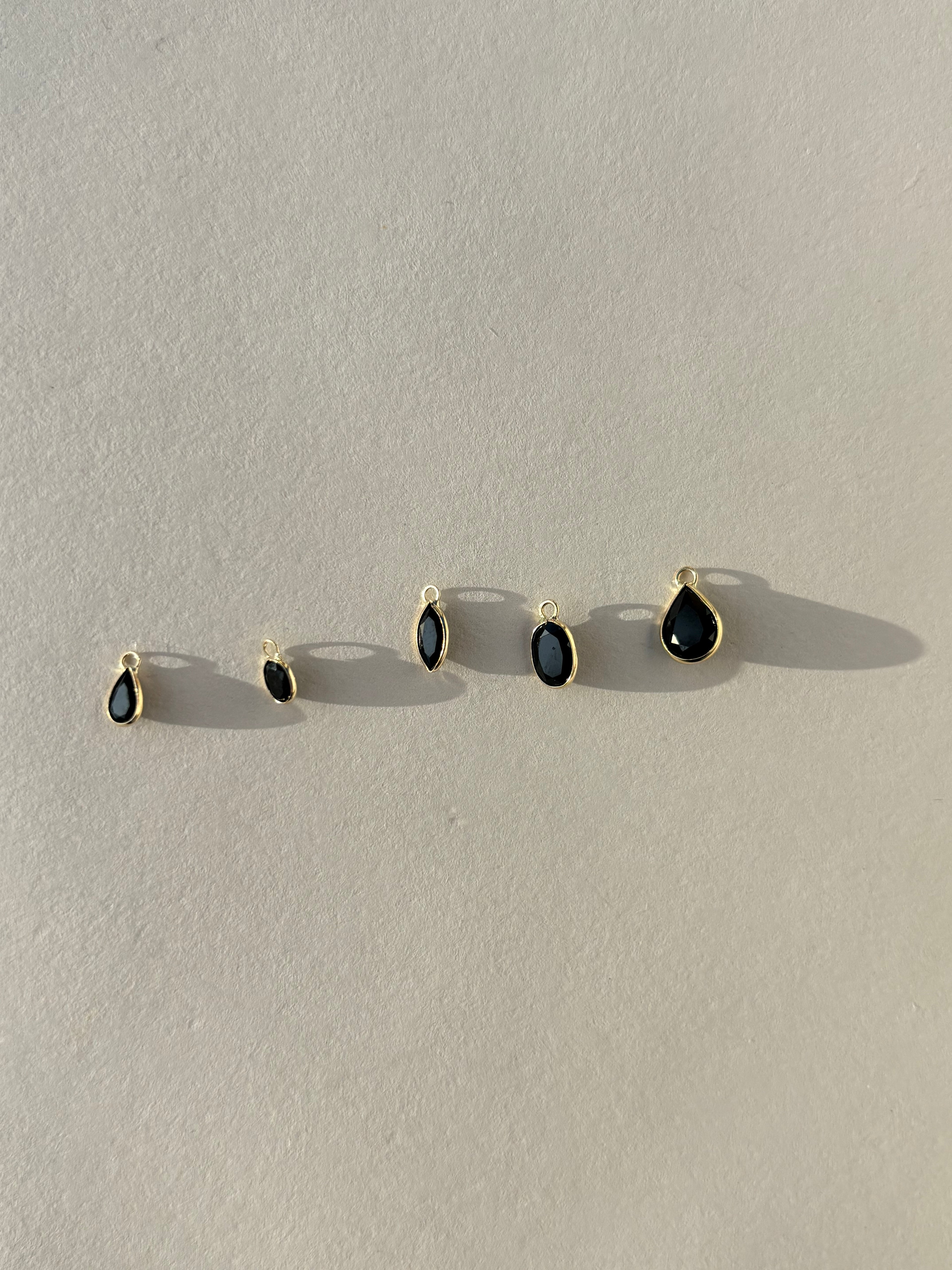 Assorted Thalken 14k gold single drop earring charms in pear, marquise, and oval shapes, displayed unattached to hoop earrings