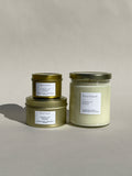 Photo of Thalken’s Boutique candle shown in three vessel options — sleek gold tins (2oz and 6oz) and a soft-glow glass jar (8oz). Bright and sunny scent profile with notes of sugared limes, mandarins, tropical fruits, and a touch of cypress