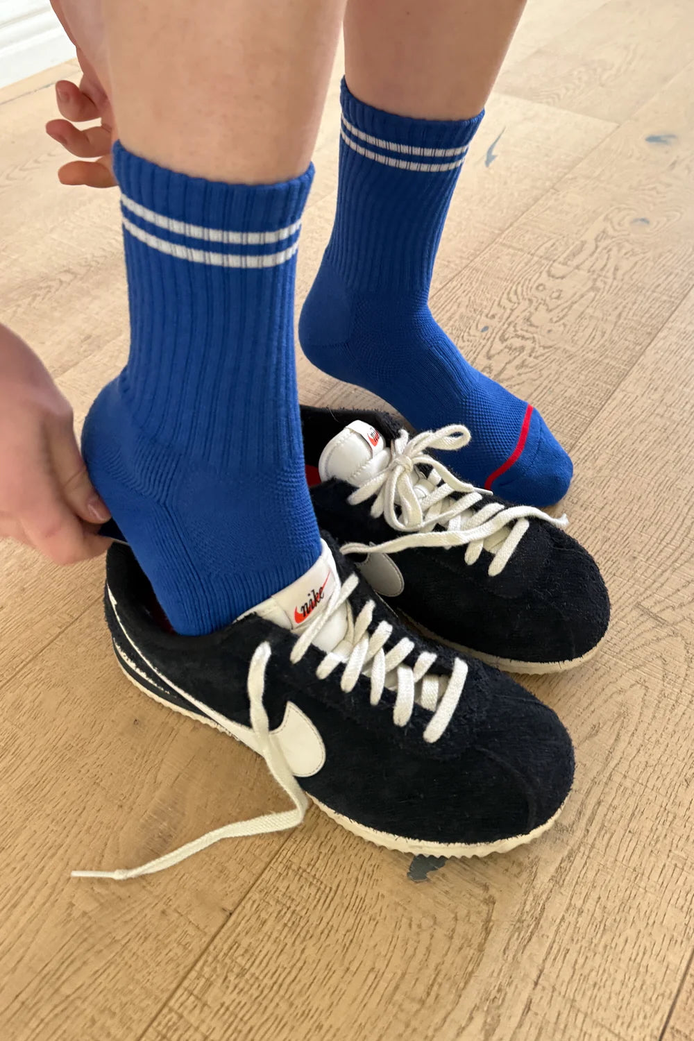 woman in blue socks putting her shoes on