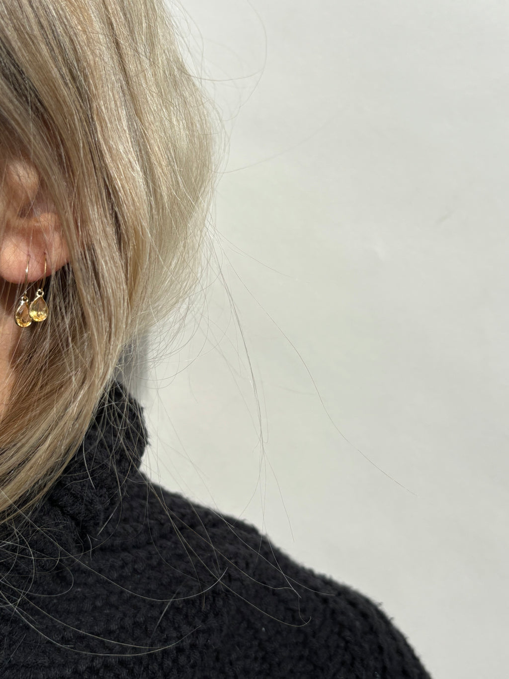 Model wearing Thalken 14k solid gold 12mm hoop earring with a large pear-shaped citrine drop in the first ear piercing, paired with a 10mm hoop and large pear-shaped citrine drop in the second ear piercing, highlighting elegant fine jewelry