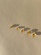 Assortment of Thalken 14k solid gold single drop earring charms in natural citrine, featuring pear, marquise, and oval shapes, displayed unattached to hoops for customizable earring styling