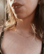 Model wearing Thalken’s dainty gold-filled birthstone necklace with a clear April 3mm bezel-set cubic zirconia charm