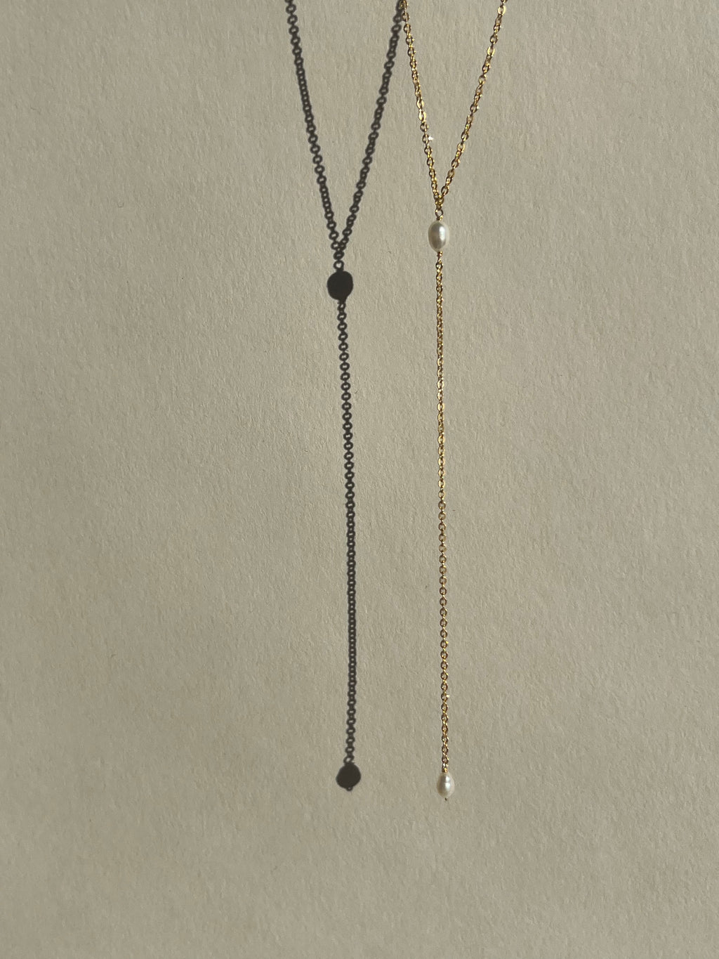 Dainty freshwater pearl lariat necklace from Thalken suspended in air, showcasing its minimalist and elegant design