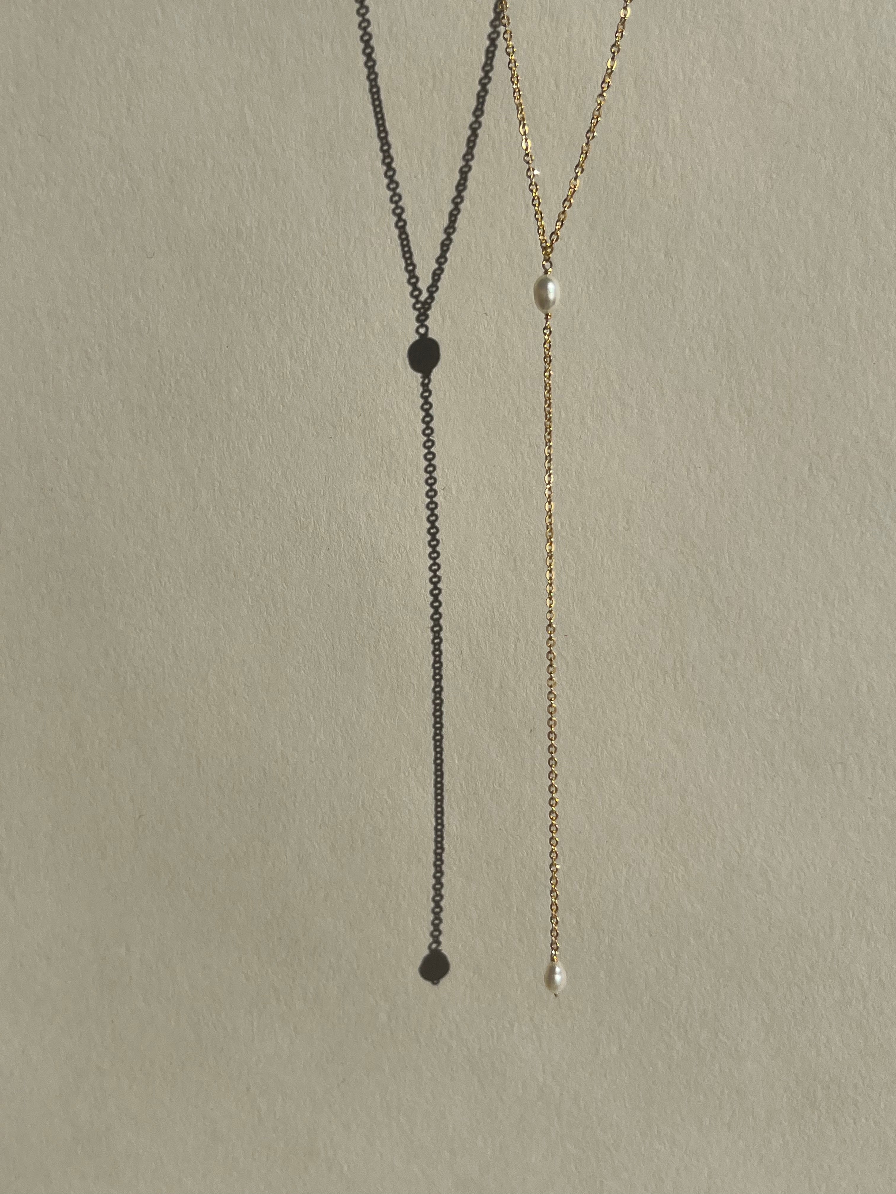 Dainty freshwater pearl lariat necklace from Thalken suspended in air, showcasing its minimalist and elegant design