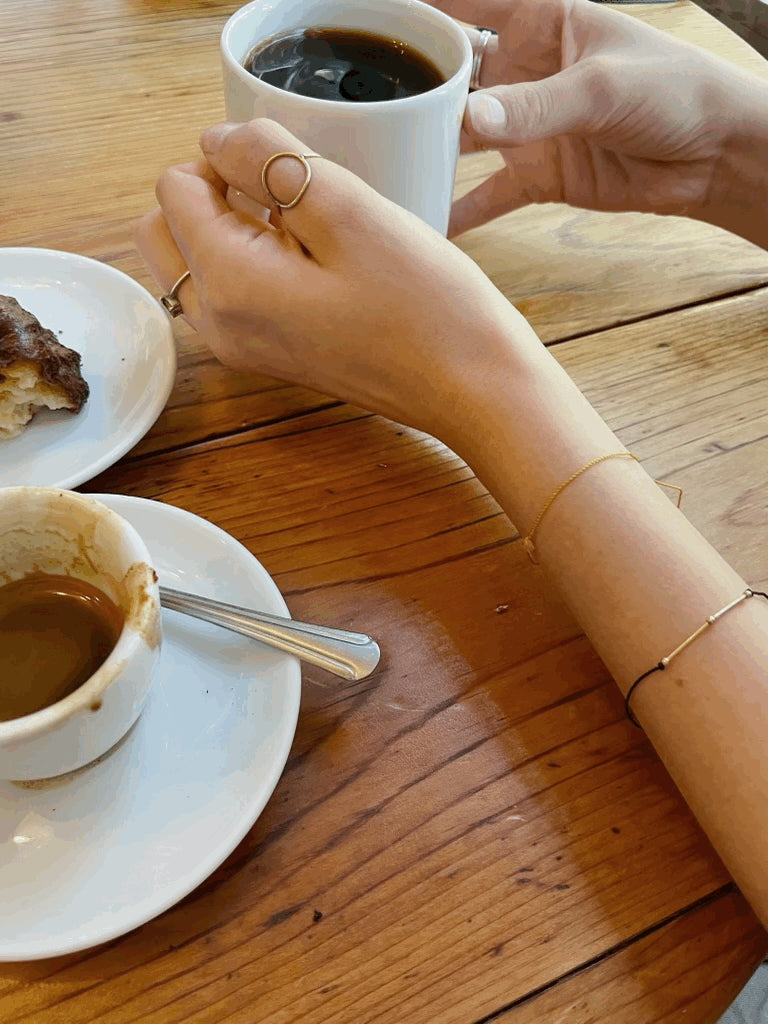Arms resting on the table to show the bracelet stack with the Thalken® Drop of Sunshine bracelet and the Thalken® Balance bracelet