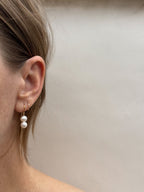 Double pearl threader earrings in first ear piercing on an ear with a tiny hoop in the second piercing