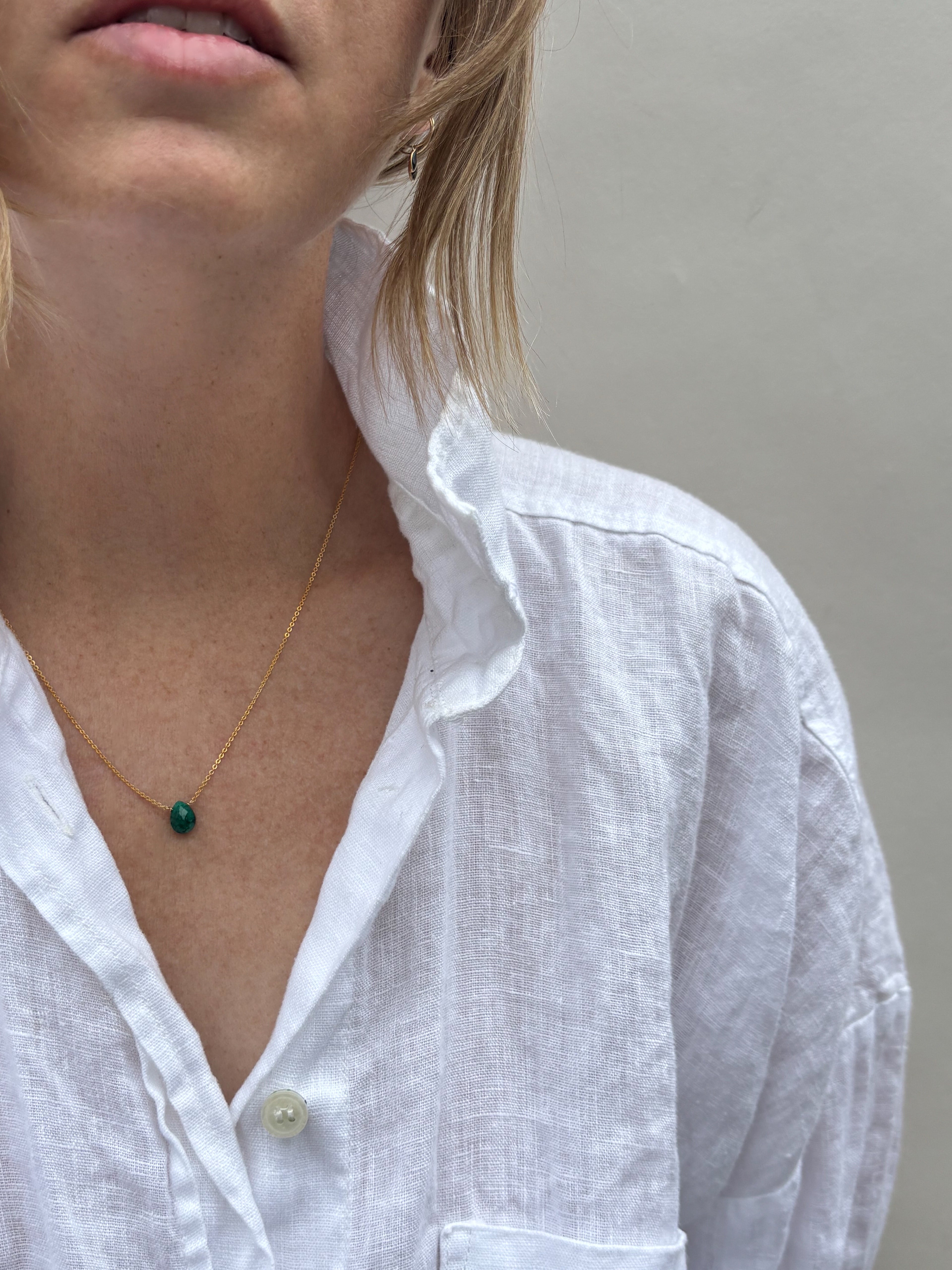 Model wearing dainty Thalken emerald drop necklace in white linen shirt