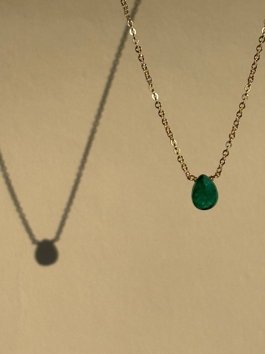 Thalken Emerald Drop Necklace with a green stone suspended in air