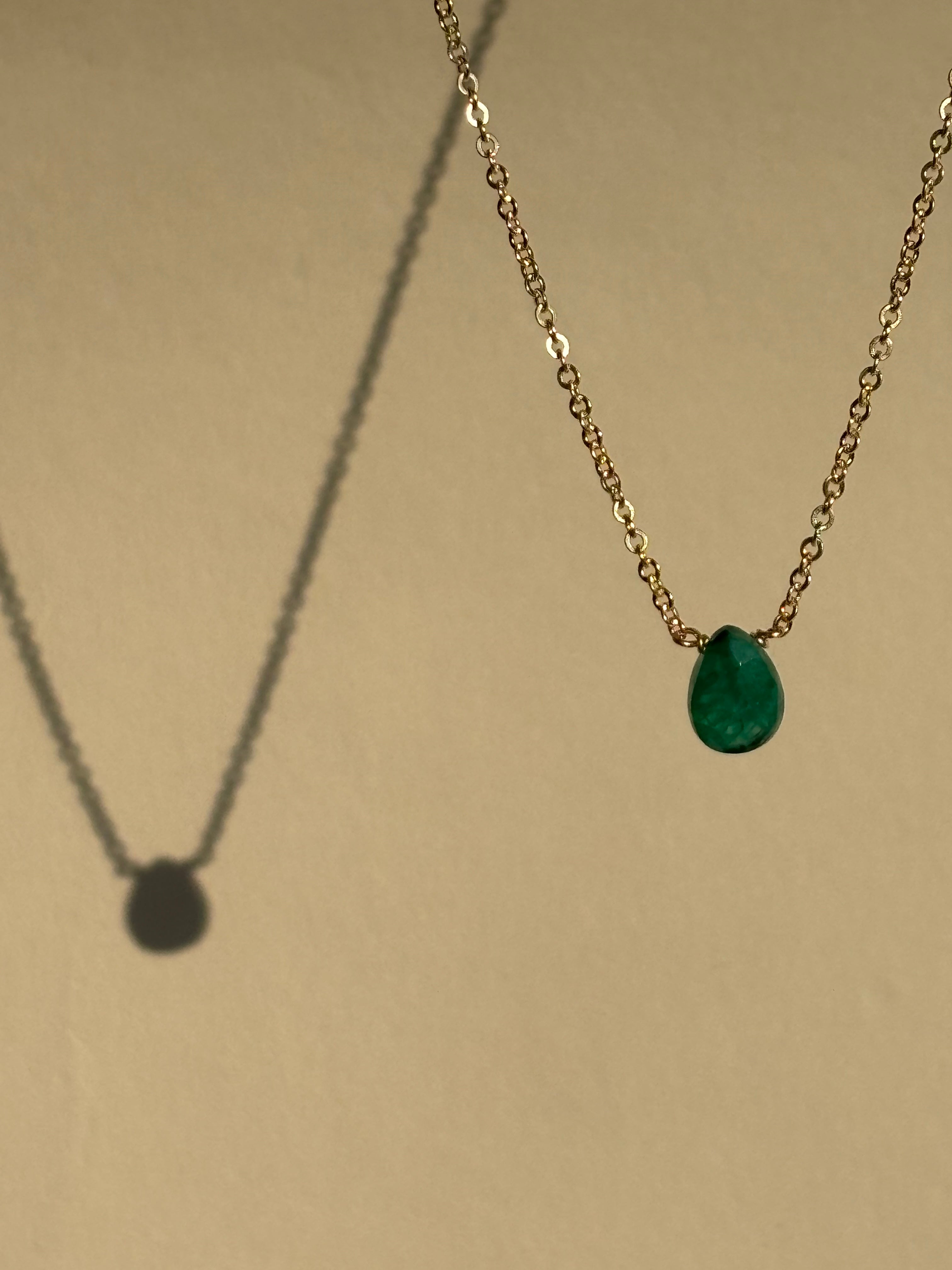 Thalken Emerald Drop Necklace with a green stone suspended in air