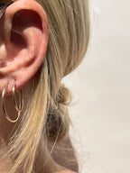 Model wearing 24mm gold-filled hoops in her first ear piercing and 20mm hoops in her second, displaying mid-size layering