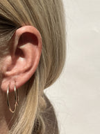 Side view of model wearing 24mm and 20mm gold-filled endless hoops in first and second earlobe piercings