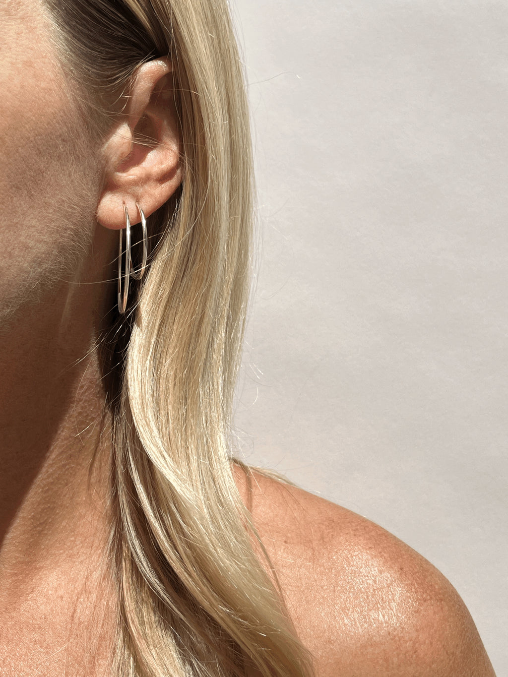 Model wearing 35mm sterling silver hoops in her first ear piercing and 24mm hoops in her second