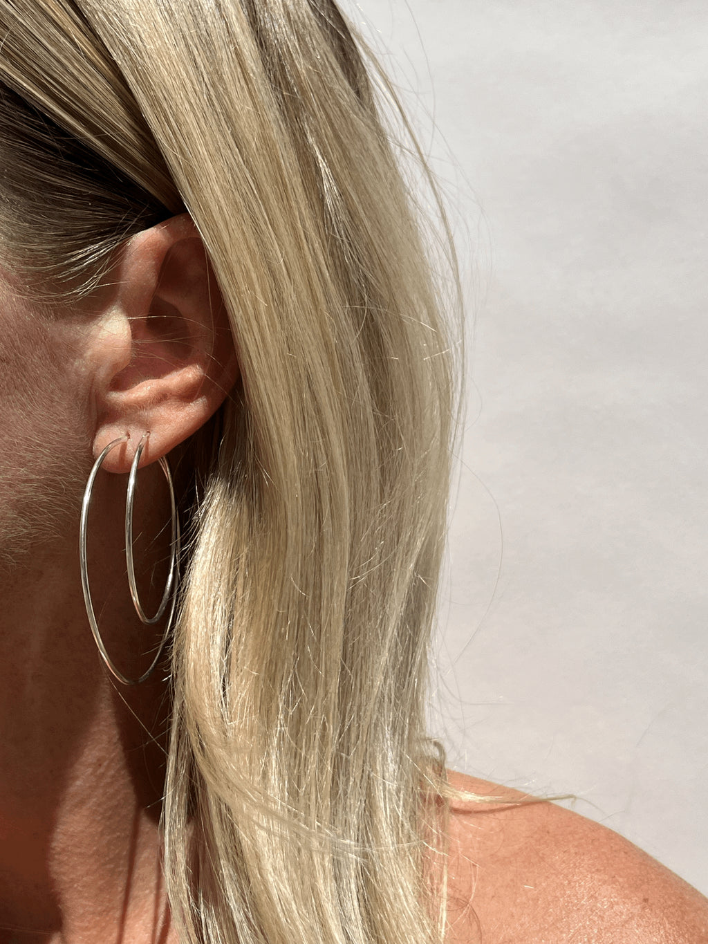 Model wearing 50mm sterling silver hoops in her first ear piercing and 40mm hoops in her second