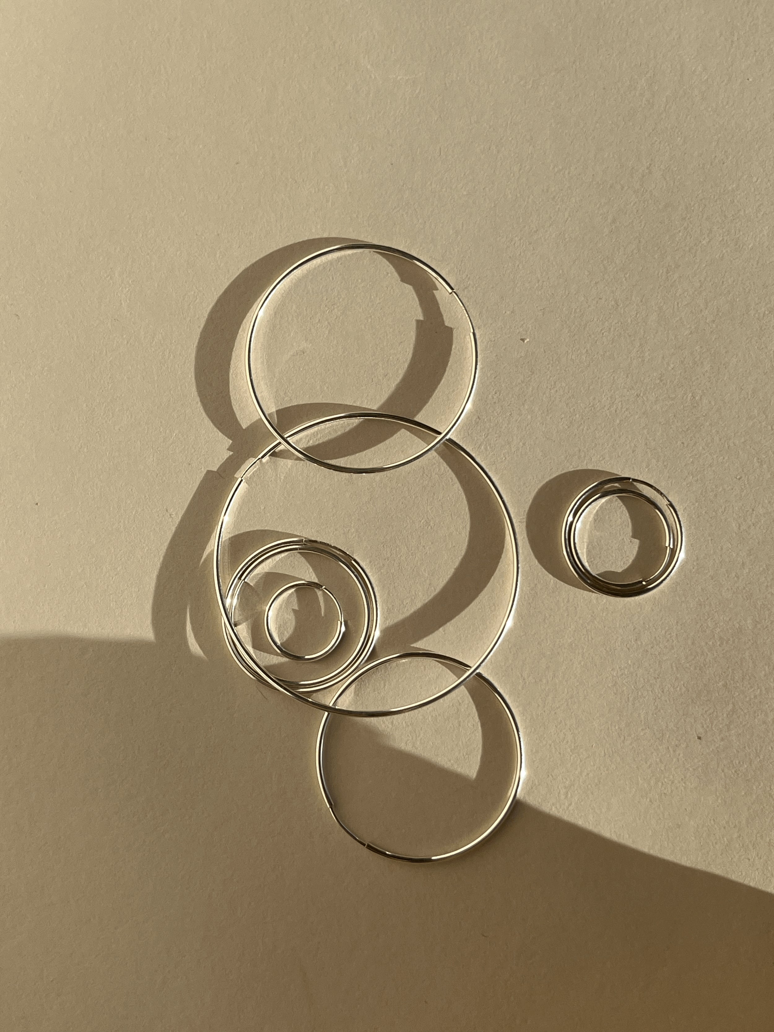 Geometric flat lay of sterling silver endless hoops in all eleven sizes arranged in a modern, bubble-inspired composition