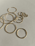 Artistic flat lay of all eleven sizes of gold-filled endless hoops arranged in a floating, bubble-like pattern, showcasing the full size range from 12mm to 50mm