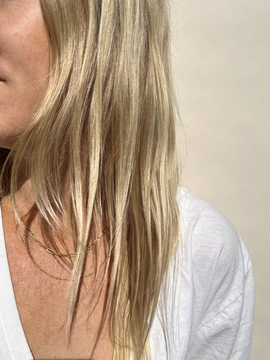 Model in white V-neck wearing 16” Original Medium Link Paperclip Necklace layered with 18” Minimalist Bead Chain Necklace, both yellow gold-filled