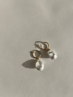 The Grand Freshwater Pearl Drops displayed on a warm backdrop, showcasing their elegant gold-filled hoops and statement pearls