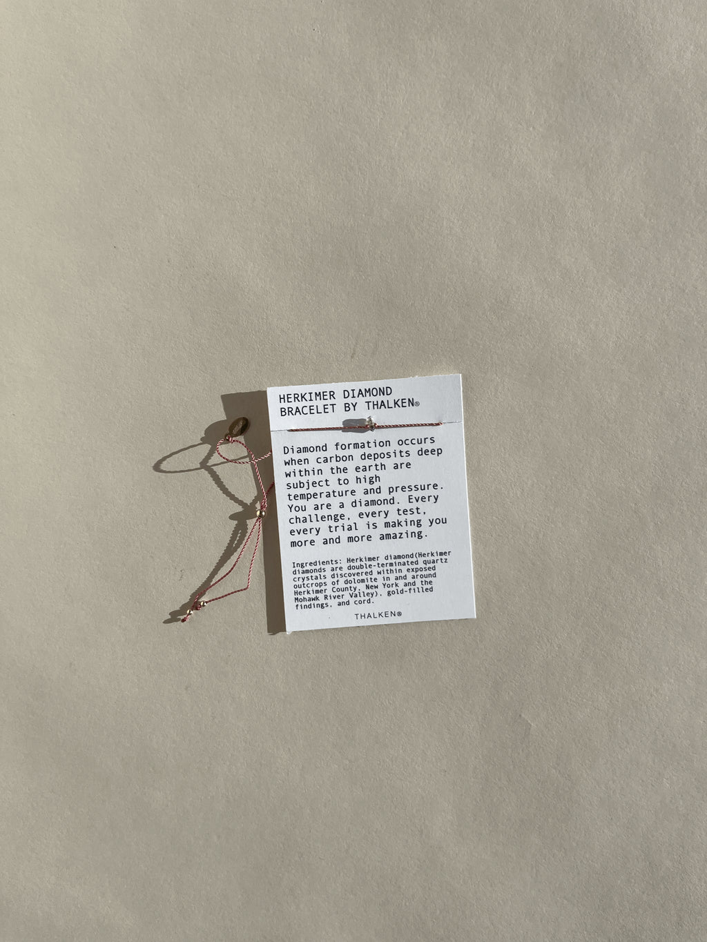 Pulled-back view of Herkimer diamond bracelet on mantra bracelet card with neutral background