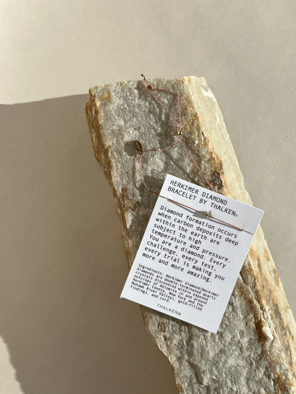 Pulled-back shot of bracelet on mantra bracelet card, styled on a rock surface