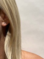 Model wearing the clear Itty Bitty Crystal Stud earrings in sterling silver in her first and second ear piercings, showcasing their delicate everyday sparkle