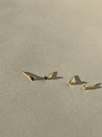 Distant shot of two pairs of tiny yellow gold-filled cubic zirconia stud earrings, featuring one black pair and one clear pair, styled for minimalist everyday wear